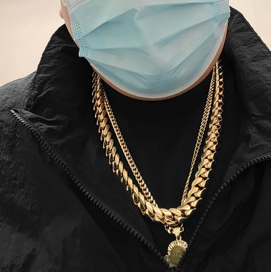 A party goer wearing two large 14kt gold chains and a face mask